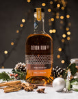 Bottle of Devon Rum Co Honey Spiced Rum with festive decorations on a dark background with fairy lights.
