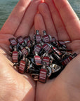 Small Enamel Devon Rum Co Spiced Rum Bottle Pins in Hands Over the Water in Salcombe, Devon