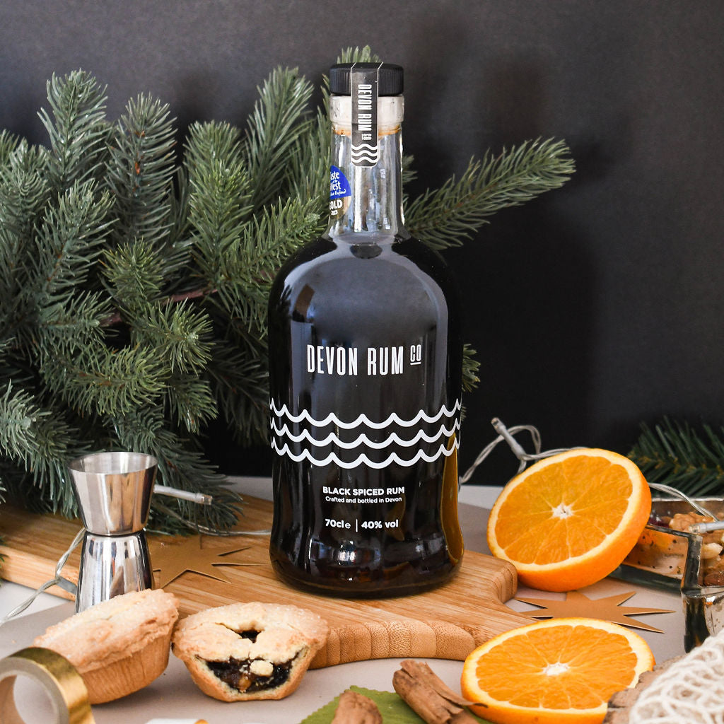 Devon Rum Co Black Spiced Rum in a festive setting with mince pies and orange slices.